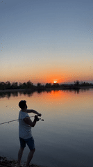 Man fishes at lake during sunset