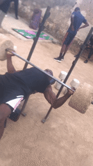 Man exercises with concrete weights outdoors in Jos