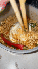 Person enjoys ramen dinner in purple-lit room in Raanana
