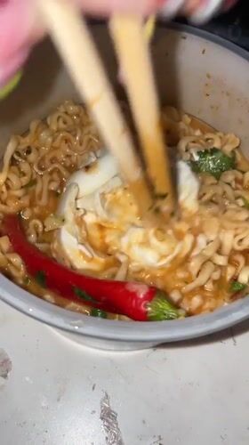 Person enjoys ramen dinner in purple-lit room in Raanana