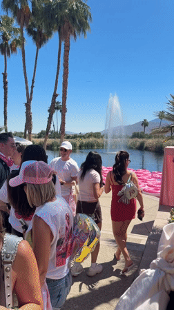People gather at fountain lake with pink tubes in La Quinta
