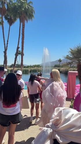 People gather at fountain lake with pink tubes in La Quinta