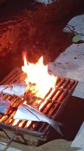 Man grills fresh fish over open fire in Juan Griego