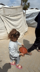Child carries pan of liquid across Gaza street