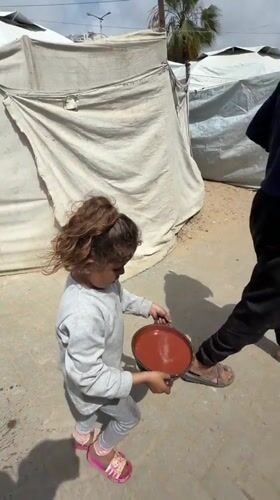 Child carries pan of liquid across Gaza street