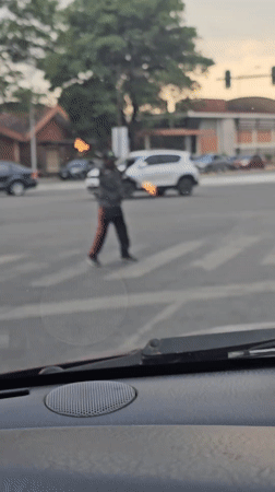 Man juggles flaming batons while crossing street in Puebla