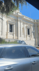 Car passes classical government building in Rome