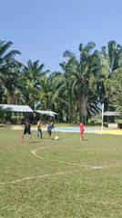 Five people play casual soccer in sunny Blangriek, Indonesia
