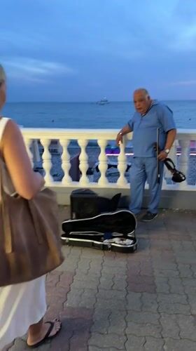Violinist plays Sochi's Black Sea promenade at sunset