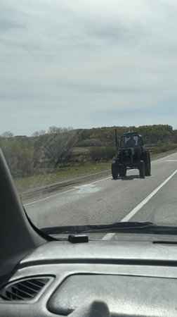 Camouflaged tractor crosses road in Russian village
