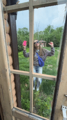 Woman photographs rural scene with pink phone in Birobidzhan