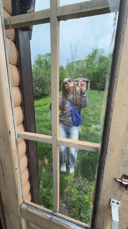 Woman photographs rural scene with pink phone in Birobidzhan