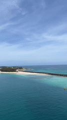 Aerial view captures tropical shoreline with breakwater and island