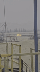 Industrial flare and still water in a hazy remote landscape