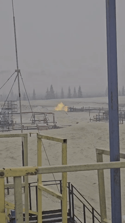 Industrial flare and still water in a hazy remote landscape