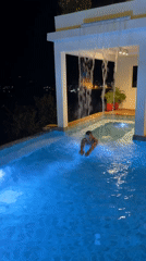 Man enjoys nighttime swim in illuminated Thailand pool