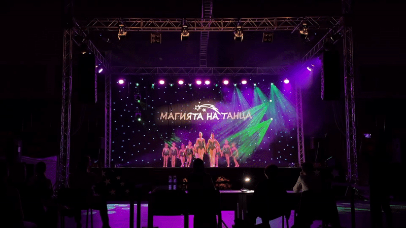 Dance performance featuring traditional costumes and Cyrillic stage backdrop