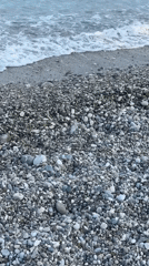 Witness documents pebble beach with waves and distant island
