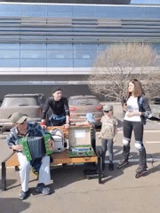 Street musician plays accordion outside modern building