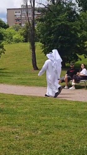 Two people in white robes walk park path in Sofia