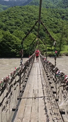 Tourist crosses ribbon-decorated suspension bridge in Abkhazia