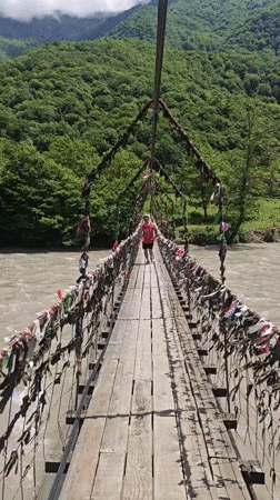 Tourist crosses ribbon-decorated suspension bridge in Abkhazia