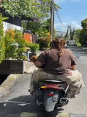 Woman rides scooter with dog in North Kuta, Indonesia