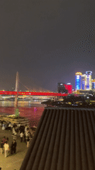 Crowds gather at Chongqing waterfront viewing illuminated bridge cityscape