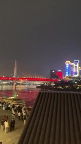 Crowds gather at Chongqing waterfront viewing illuminated bridge cityscape