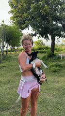 Woman holds puppy in field in Kuta Selatan