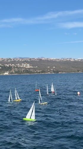 RC sailboats sail near Opatija boatyard under clear skies