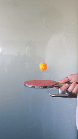 Person bounces ping-pong ball on paddle in Riga