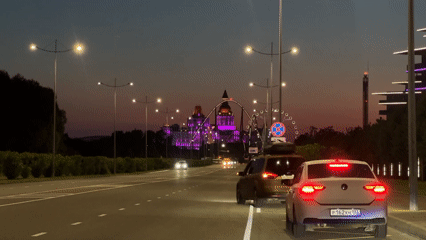 Evening traffic flows past illuminated Sochi amusement park