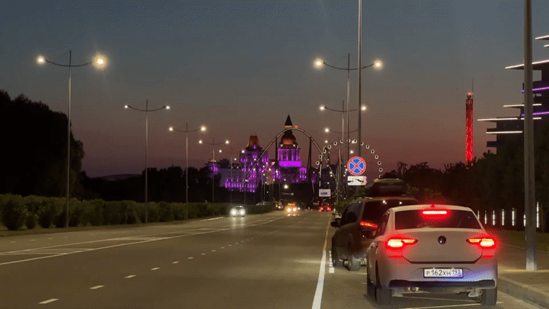 Evening traffic flows past illuminated Sochi amusement park