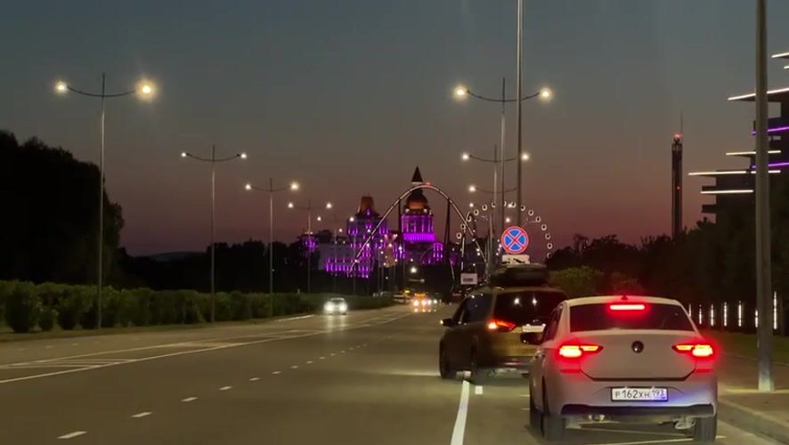 Evening traffic flows past illuminated Sochi amusement park