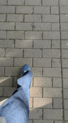 Person walks tree-lined brick sidewalk in Madrid park
