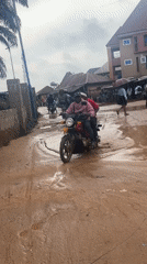 Motorcycles wade through waist-deep flooding in Ihiagwa, Nigeria