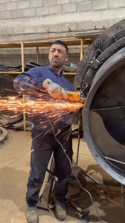 Worker operates angle grinder on metal cylinder in Montenegro