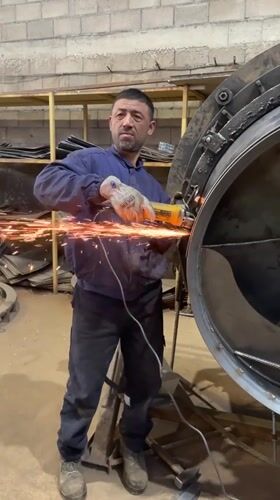 Worker operates angle grinder on metal cylinder in Montenegro