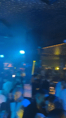 Nightclub scene features DJ, crowd, costumed performers dancing