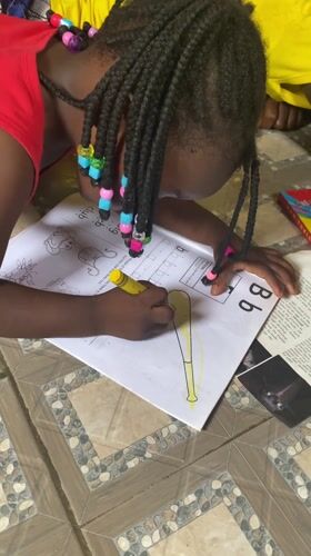 Child practices letters and coloring at home in Nigeria