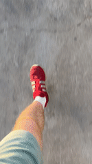 Person in red sneakers walks on textured pavement in Tel Aviv