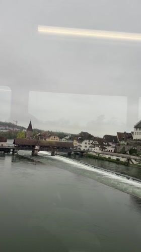 Train passenger views Bremgarten's river and covered bridge