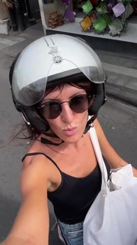 Scooter rider cruises sunny Kuta streets, selfie in hand