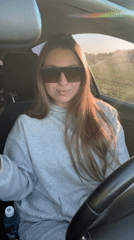 Woman removes sunglasses, smiles at camera in Omsk