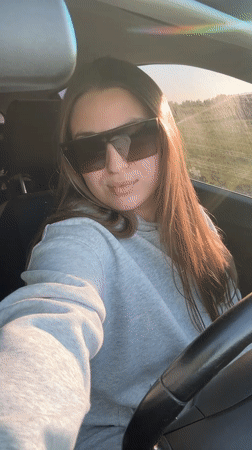 Woman removes sunglasses, smiles at camera in Omsk