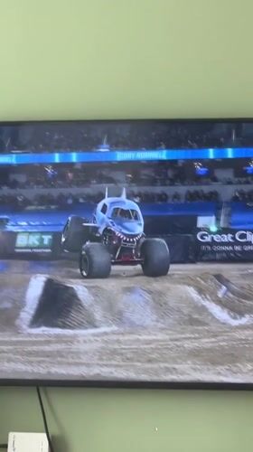 Monster truck rally on screen, toy gorilla in the crowd