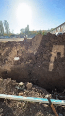 Small excavator digs trench near Sofia building in early morning