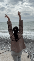 Woman poses for photos on Sochi beach during overcast afternoon