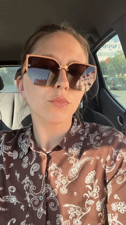 Woman records car selfies in Podgorica on sunny afternoon